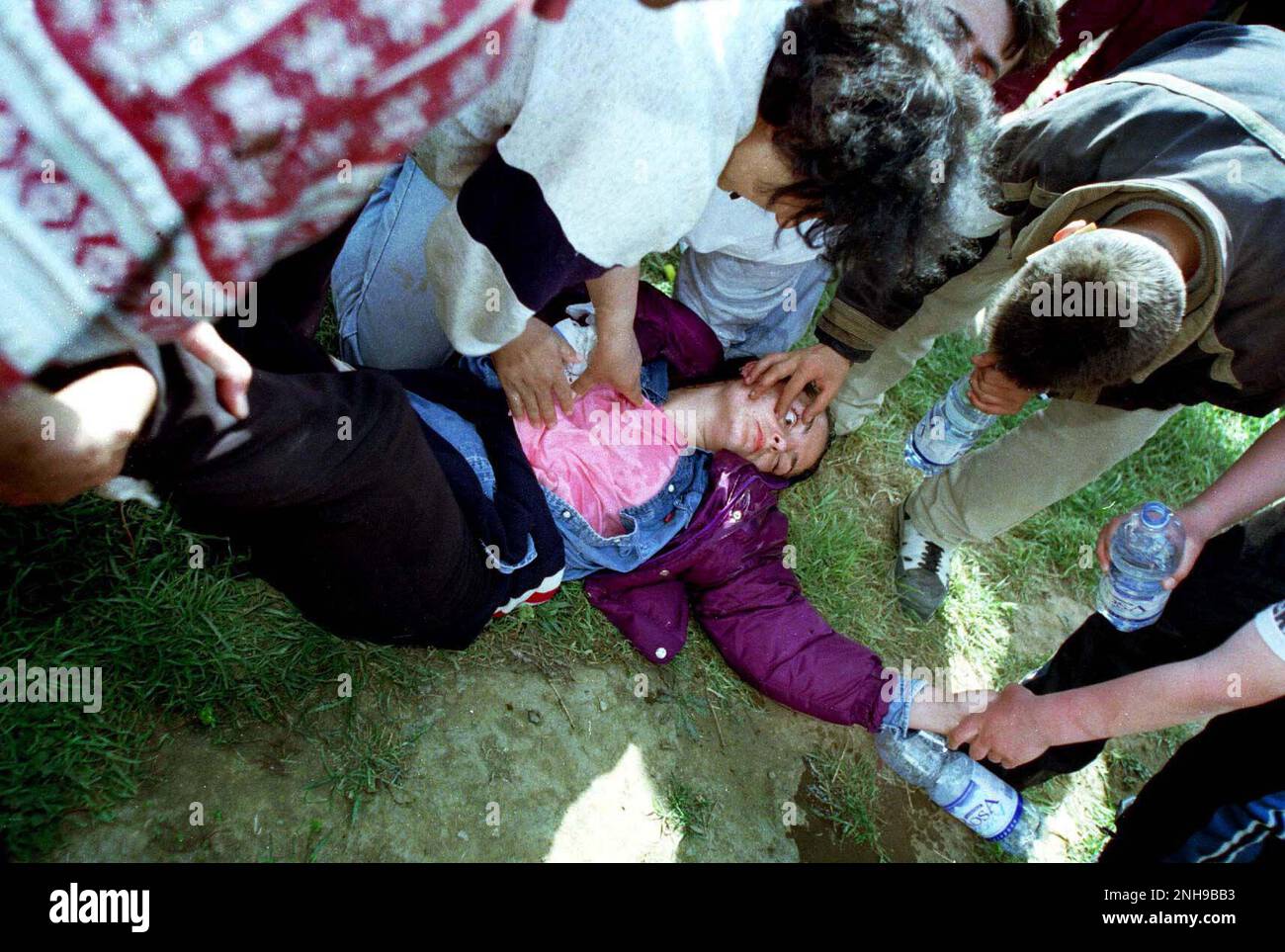 Woman refugee faints in heat having arrived in Northern Macedonia via bus from the boarder crossing. Brazda refugee camp in Macedonia April 1999. The camp was run by NATO but  turned over  to UNHCR. Macedonia. Picture garyrobertsphotography.com Stock Photo