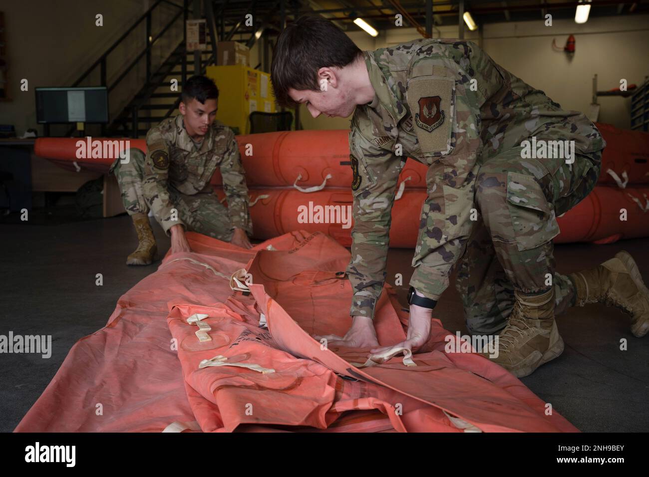 U.S Air Force Airman 1st Class Zachary Harrison, 100th Operations Support Squadron aircrew flight equipment apprentice, and A1C Christopher Schultz, 100th OSS AFE journeyman fold and store an Emergency Life Raft at Royal Air Force Mildenhall, England, July 27, 2022. Emergency Life Rafts are vacuum sealed, folded, and stored after passing annual diagnostic testing. Stock Photo