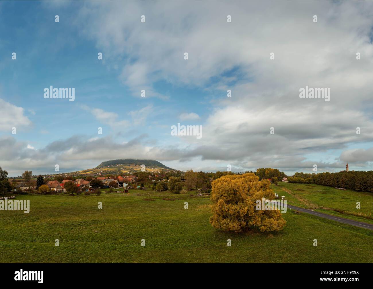 Autunm landscape in Tapolca valley Hungary. Somlo hill on the bacjgroundd. Cloudy sky and beautiful fall color trees. Stock Photo