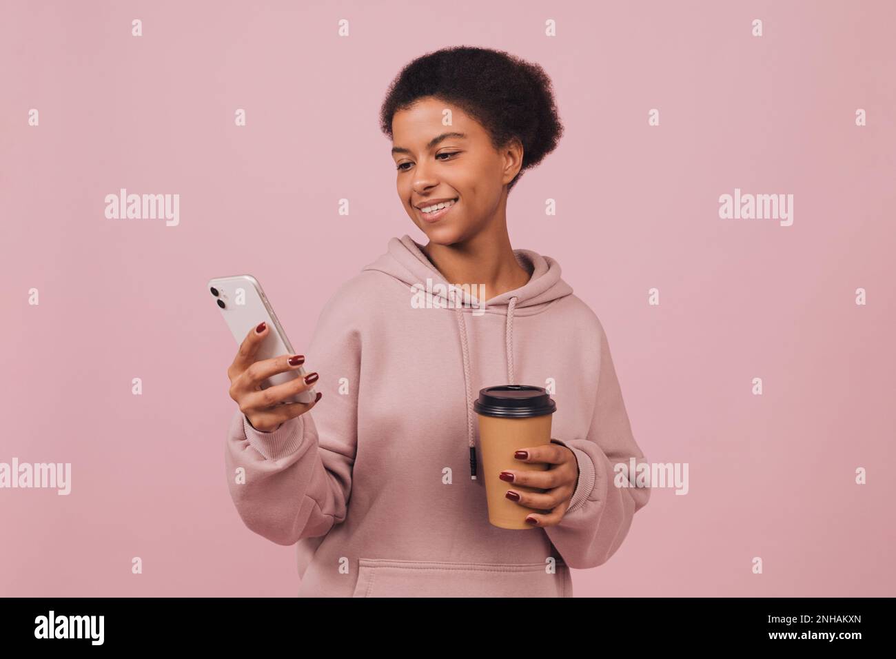 Smiling stylish girl posing over pink background. Studio portrait Stock Photo