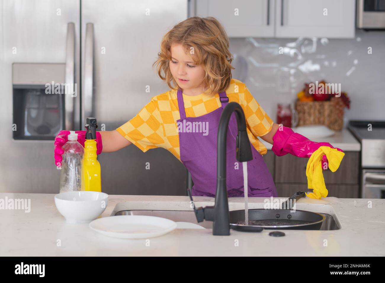 Dish washing concept. Child boy washing the dishes in the kitchen