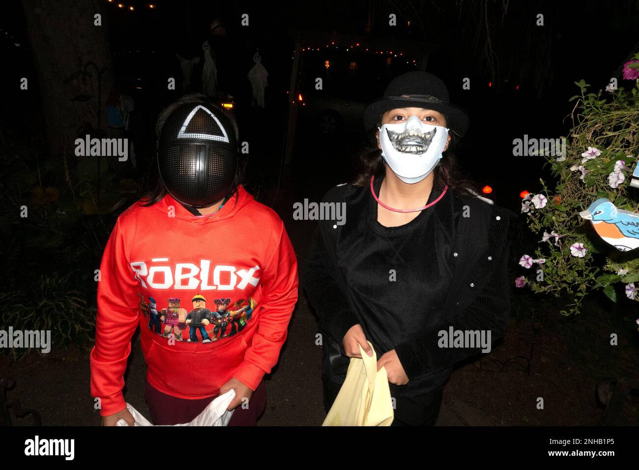 Masked trick or treaters with a red Roblox prime gaming shirt and a Halloween ghoul in costume. St Paul Minnesota MN USA Stock Photo