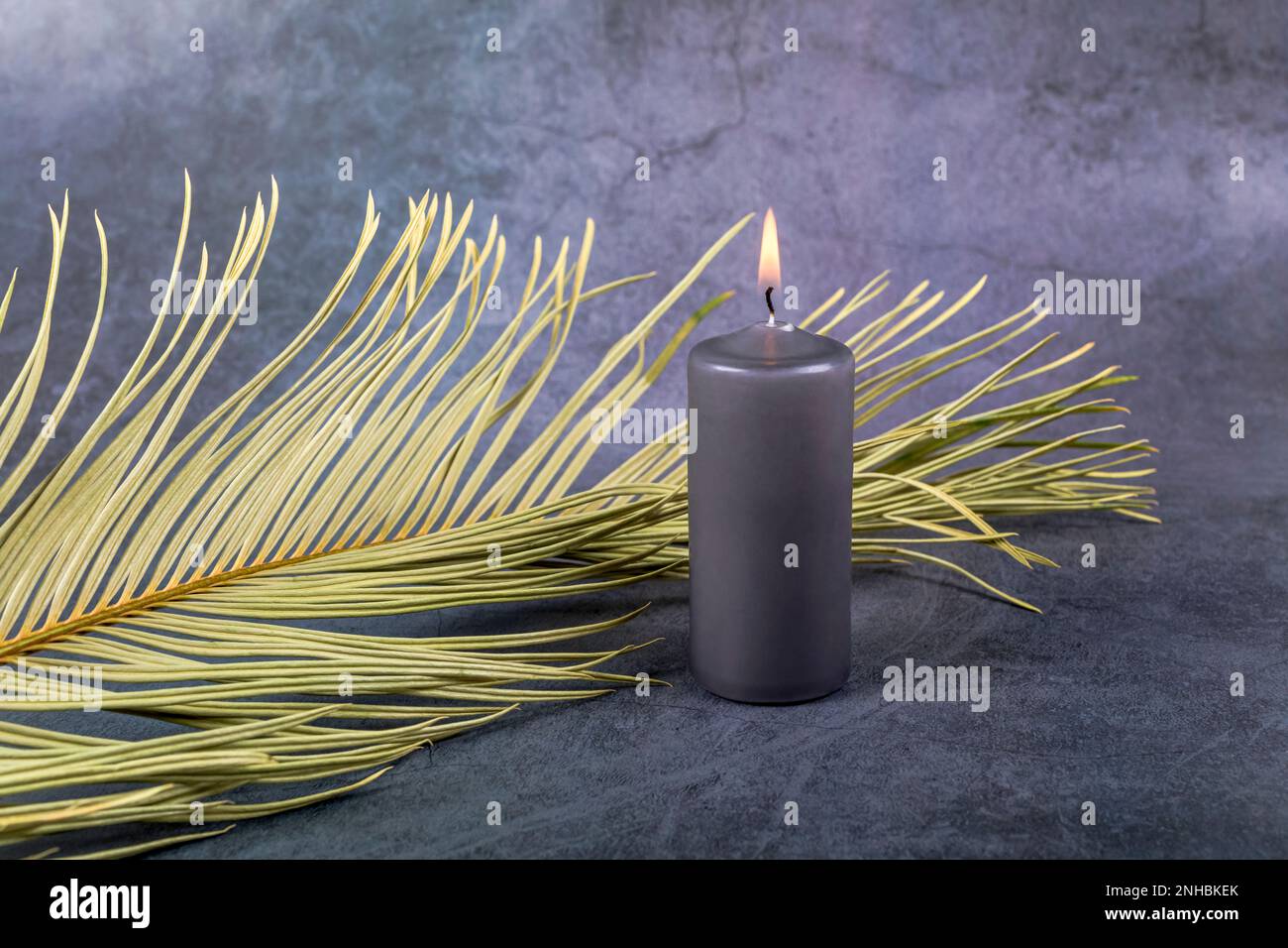 Palm leaf and burning candle. Ash Wednesday, Lent season, Holy Week, Good Friday and Palm Sunday concept. Copy space. Stock Photo