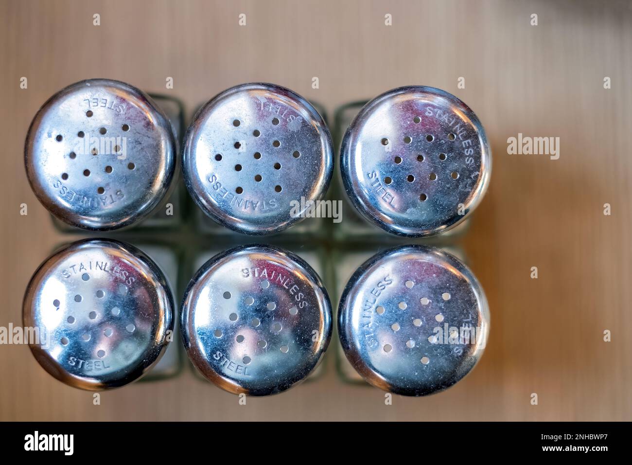 An overhead shot of metal topped six salt sellers on a coffee serve  yourself table. Customers can take the salt as needed back to their own tables Stock Photo