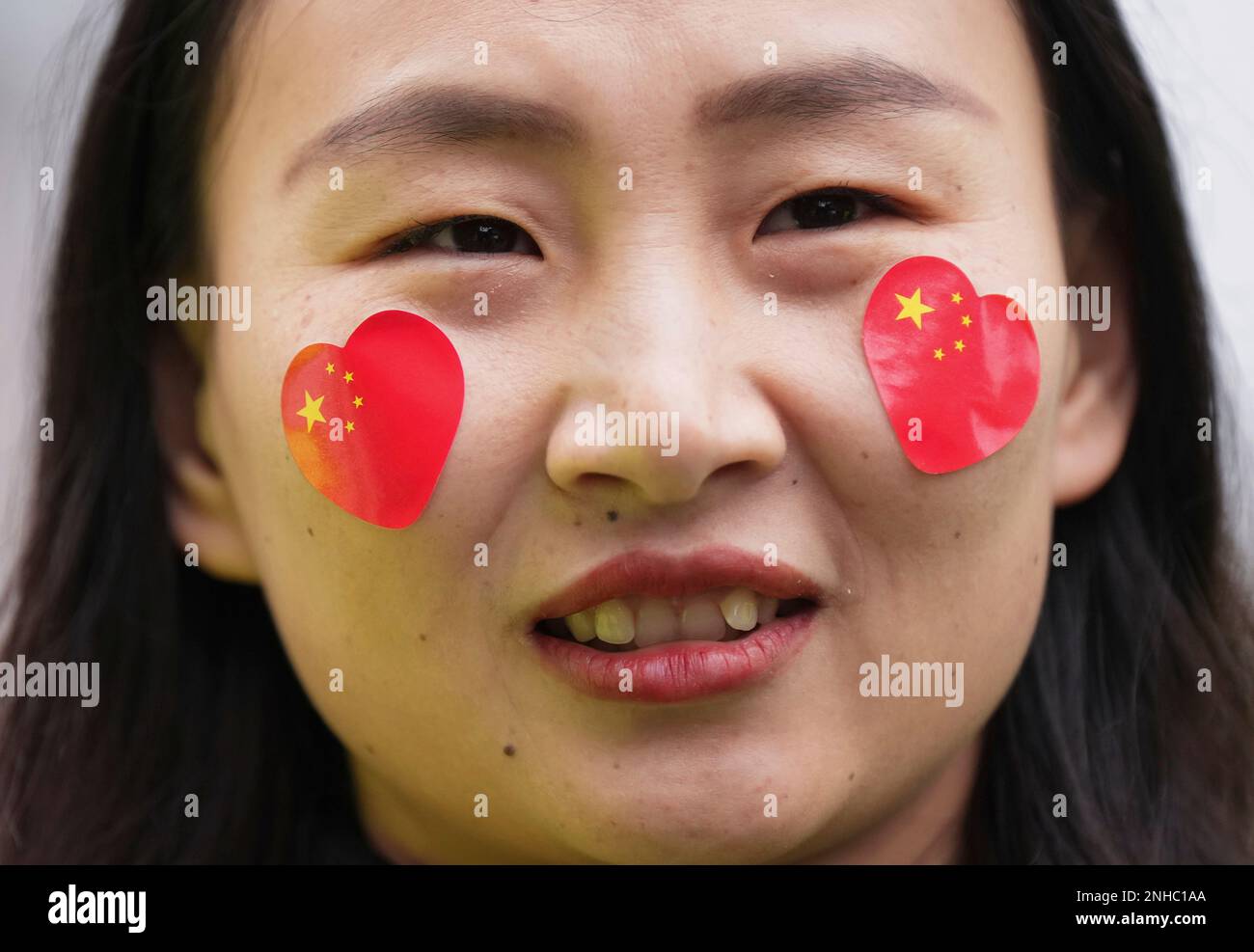 A woman wears heart stickers with the Chinese flags on her face while