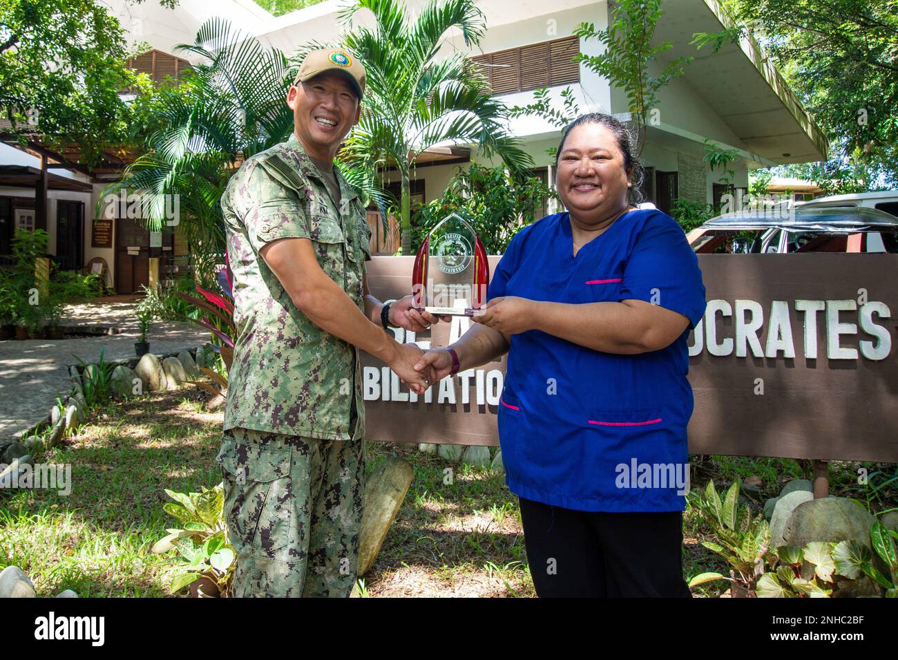 PUERTO PRINCESA, Philippines (July 28, 2022) — Capt. Hank Kim, Pacific Partnership 2022 (PP22) mission commander, left, presents a plaque to Angelica Muyco-Dantes, a physical therapist at the Dr. Jose Antonio Socrates Rehabilitation Center, during PP22. Now in its 17th year, Pacific Partnership is the largest annual multinational humanitarian assistance and disaster relief preparedness mission conducted in the Indo-Pacific. Stock Photo