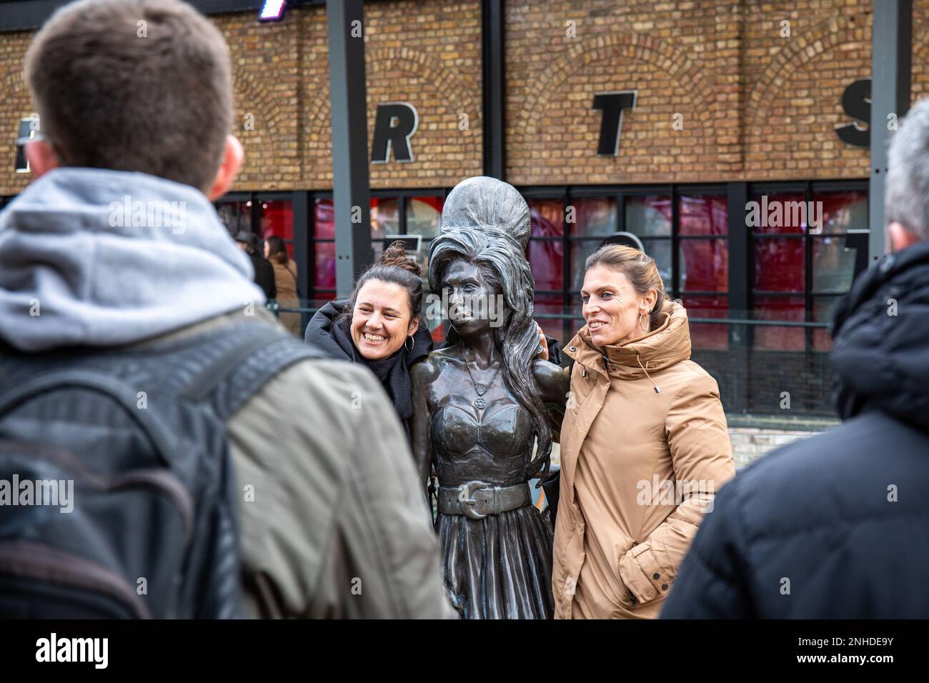 People posing with Amy Winehouse statue, designed by Scott Eaton (2014), at Stables Market in Camden Town district of London, England Stock Photo
