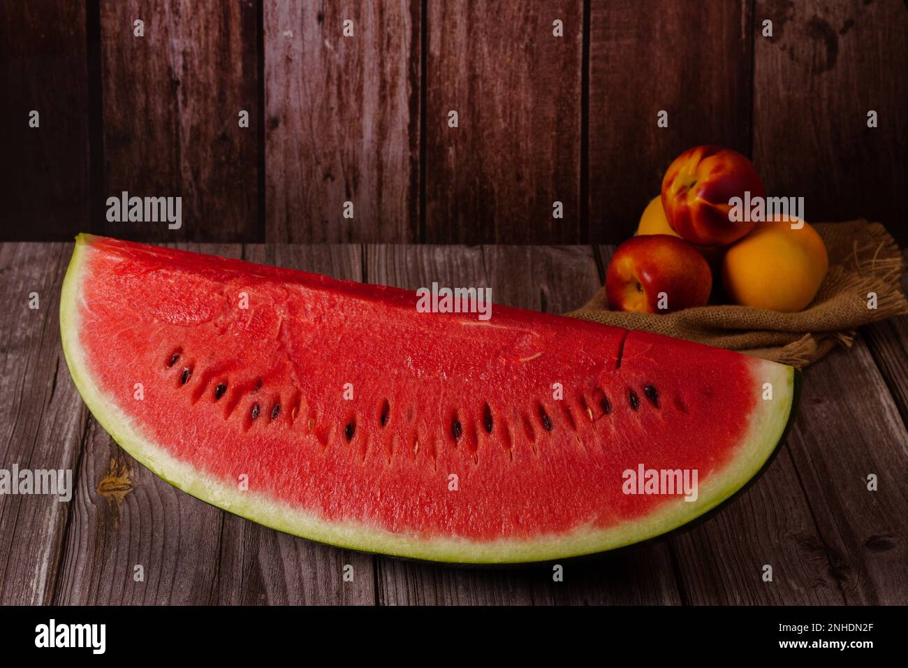 Close-up of a portion of fresh watermelon with fruit on a wooden table in the background Stock Photo