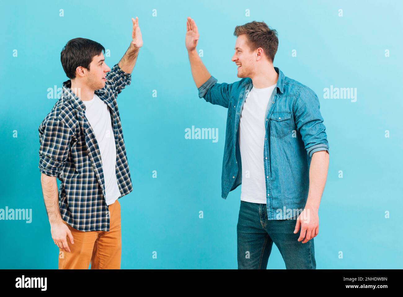young male friend giving high five against blue background. High resolution photo Stock Photo