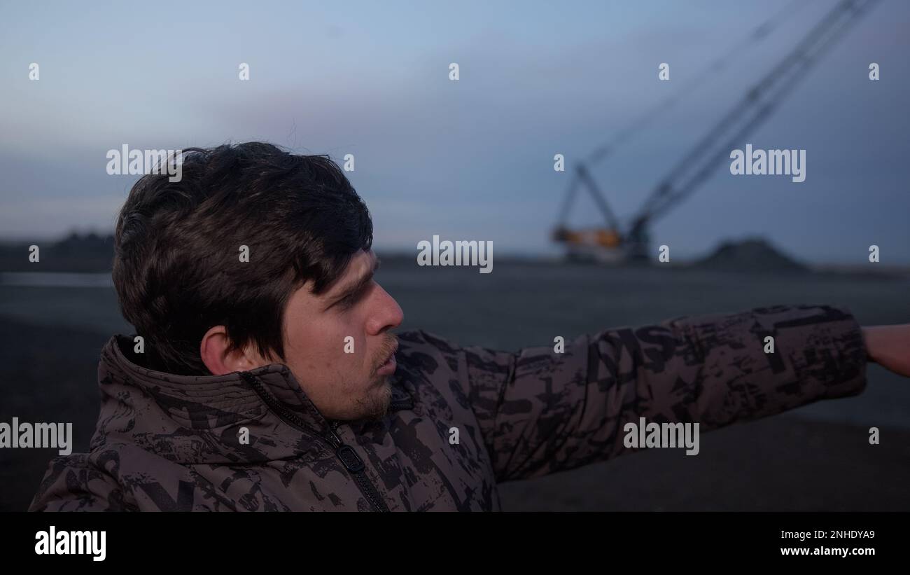 Executive man conducts video call at job site, pointing to show how things are done, industrial