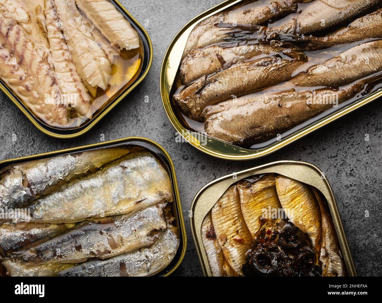Assorted canned fish in a tin over gray concrete background sardine
