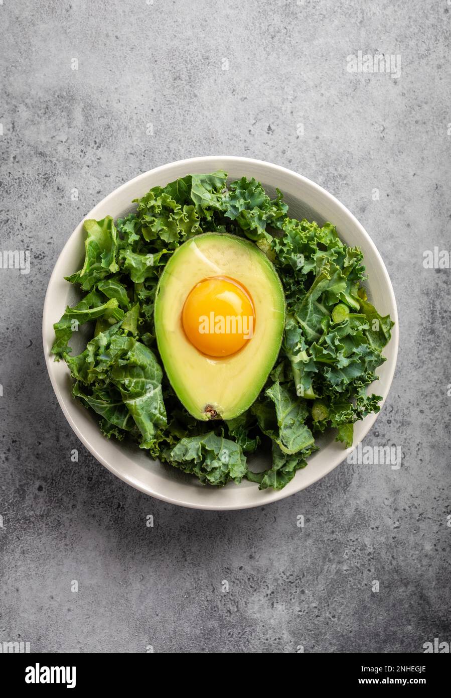 Salad bowl with kale for balanced menu, raw egg yolk in fresh cut half
