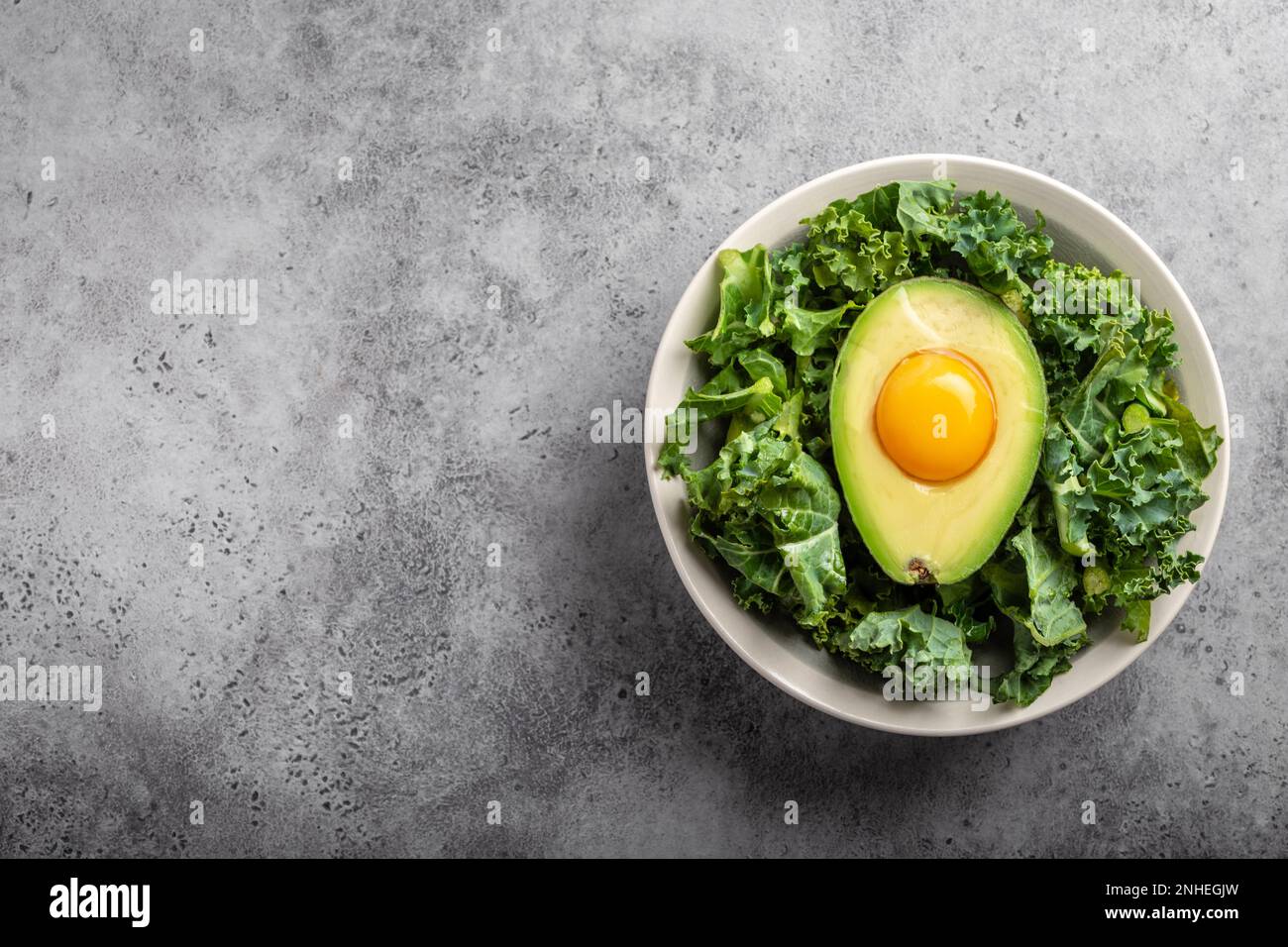 Salad bowl with kale for balanced menu, raw egg yolk in fresh cut half