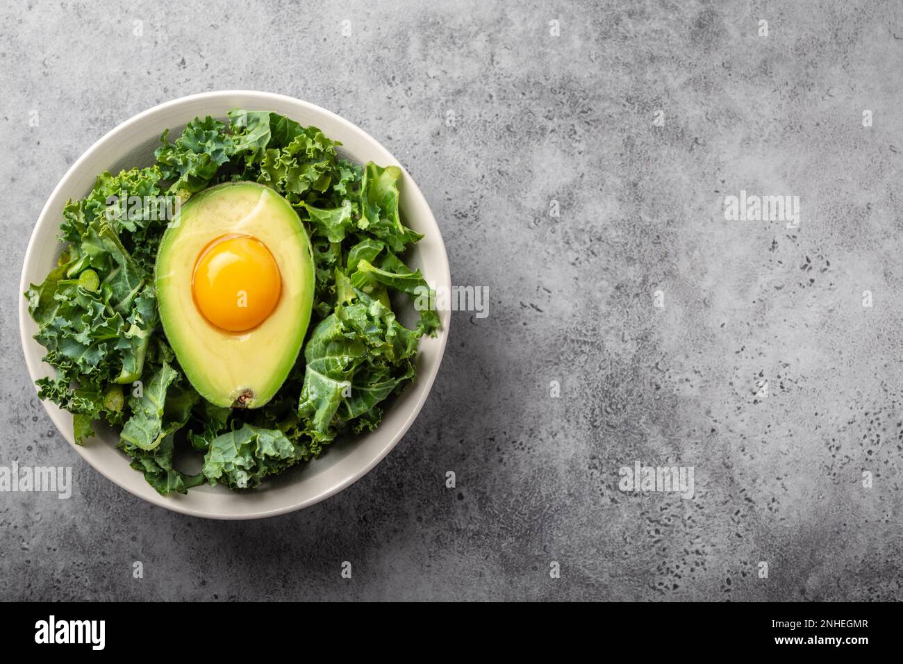 Salad bowl with kale for balanced menu, raw egg yolk in fresh cut half