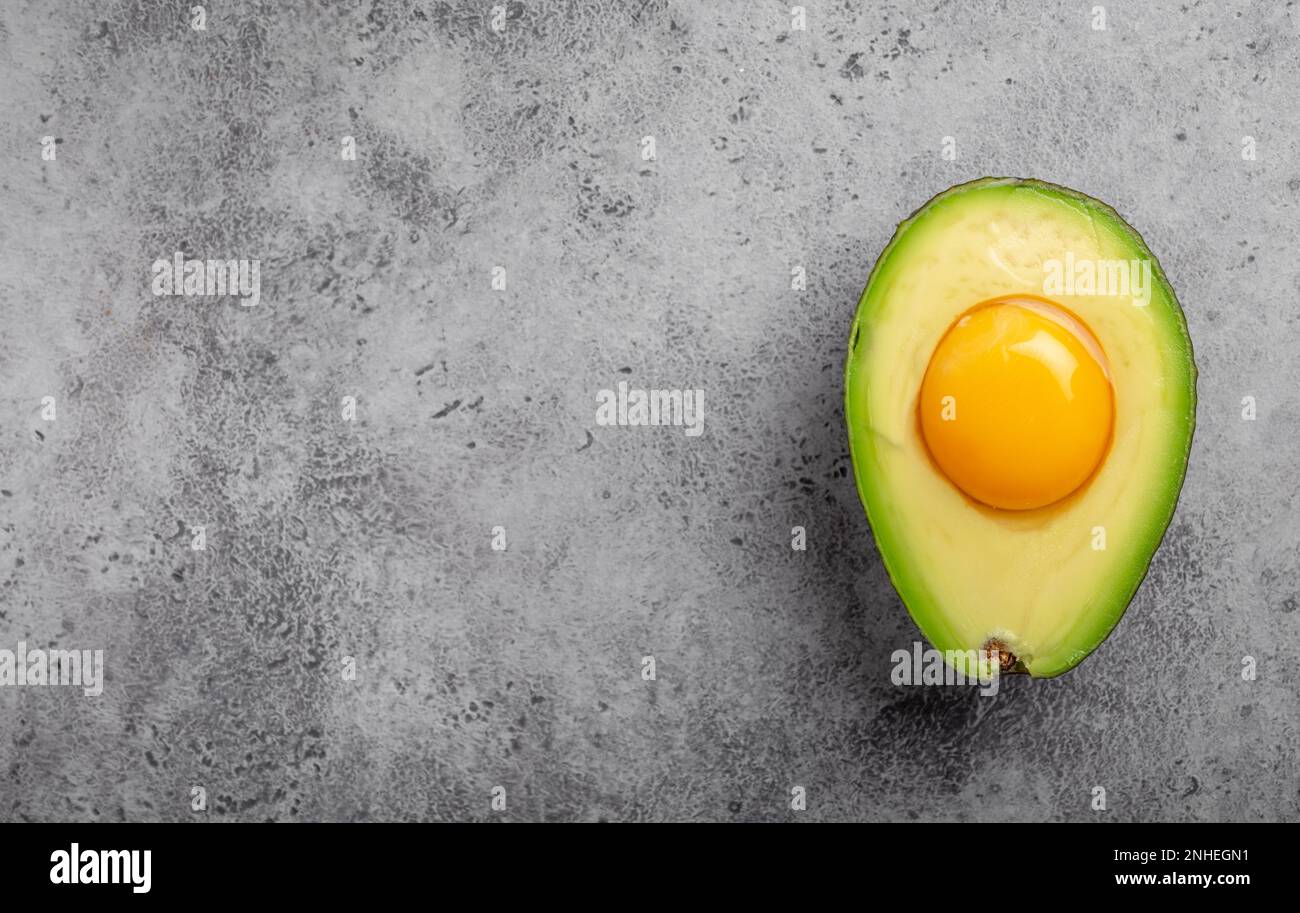 Foods rich in healthy fats for balanced nutrition raw egg yolk in fresh cut half avocado on