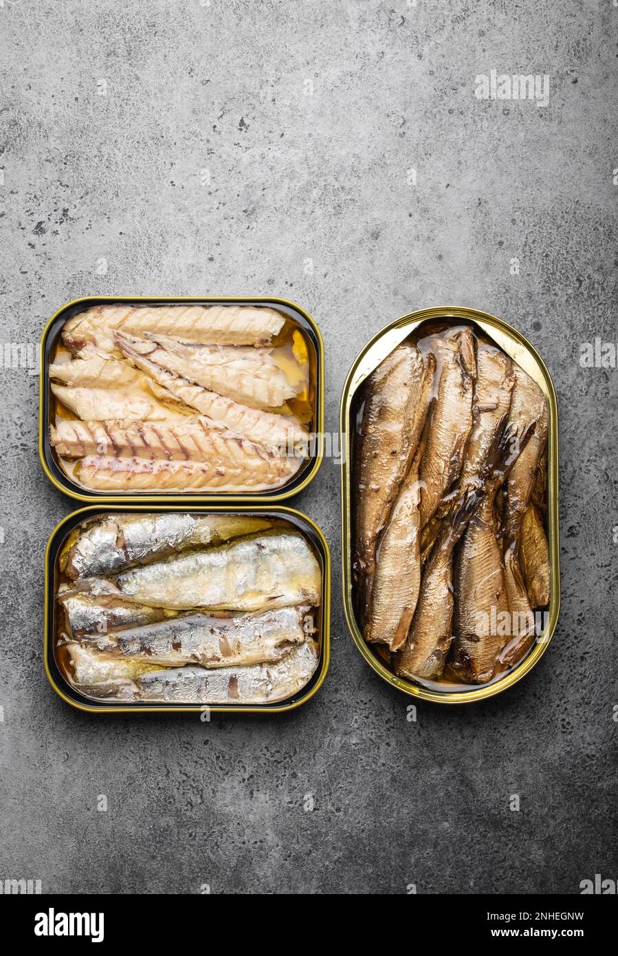Assorted canned fish in a tin over gray concrete background: sardine ...