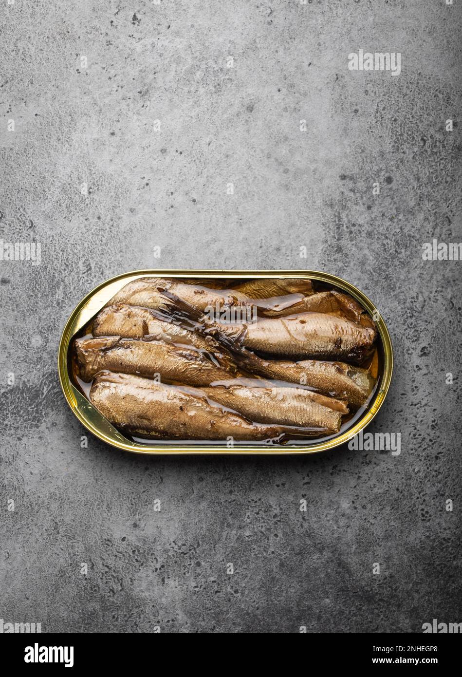 Close up and top view of smoked canned sardine in a tin over gray