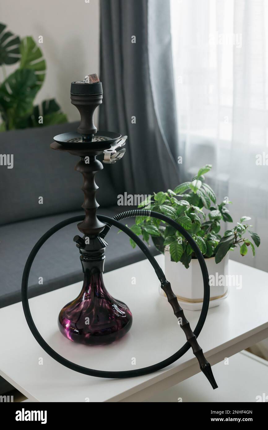 Hookah shisha with glass flask and metal bowl in room background