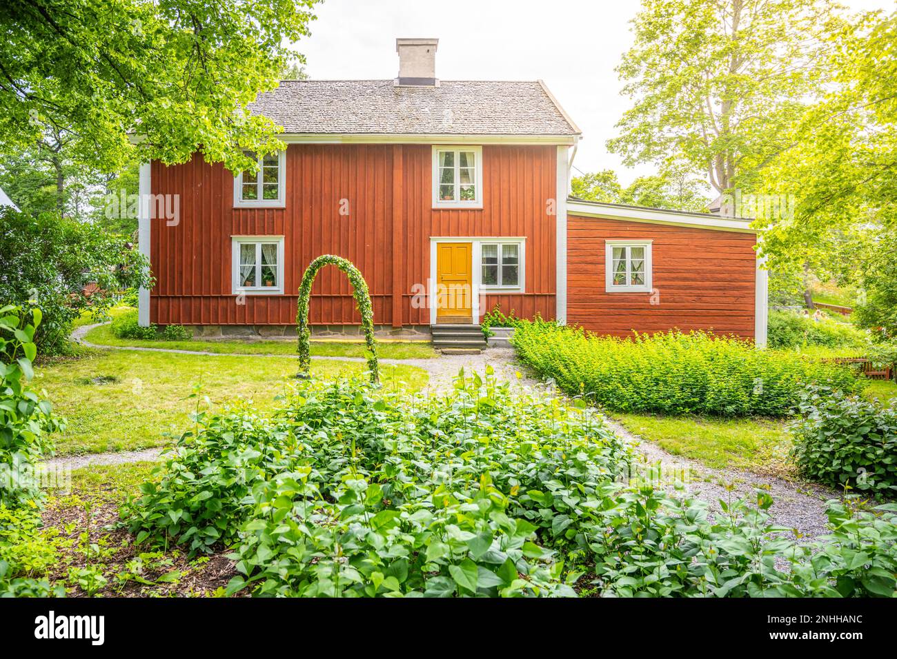 Historic red wooden house surrounded by trees and grass at Skansen ...