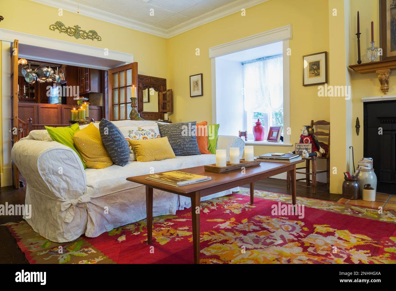 Teak wood coffee table, sofa with colourful cushions in living room