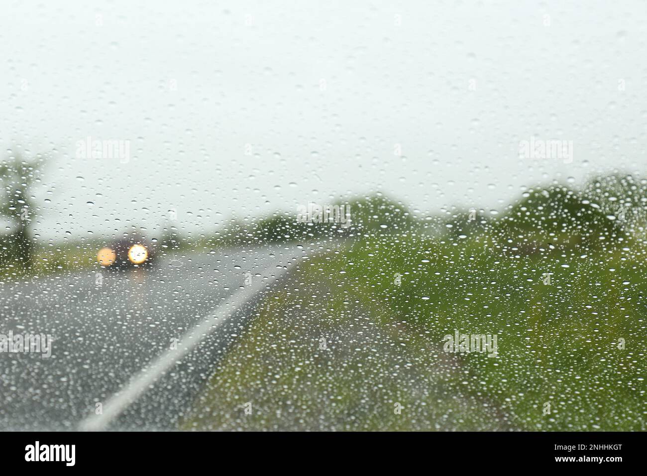 Blurred view of country road through wet car window. Rainy weather ...