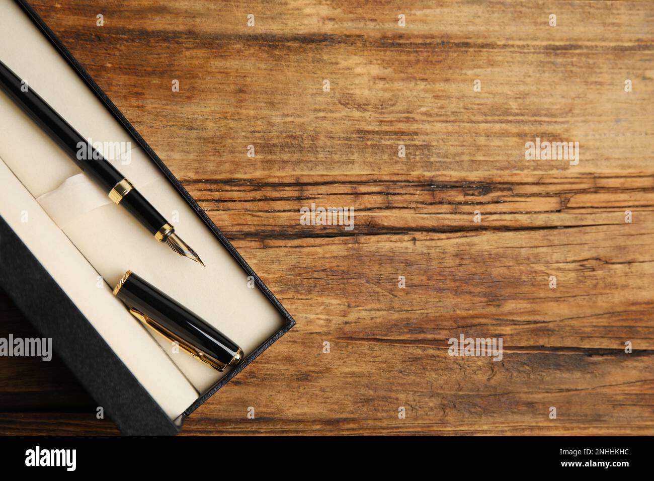 Beautiful fountain pen in box on wooden table, top view. Space for text