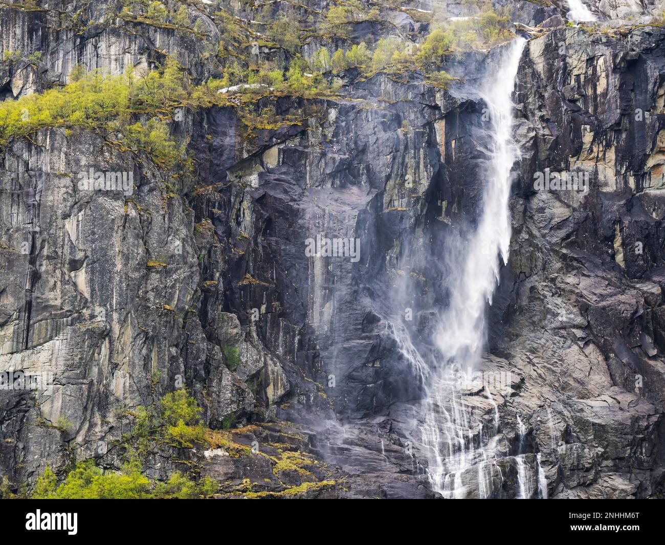 A view of a waterfall on the steep wall of mountains with the Myklebustbreen glacier at the top, Norway. Stock Photo