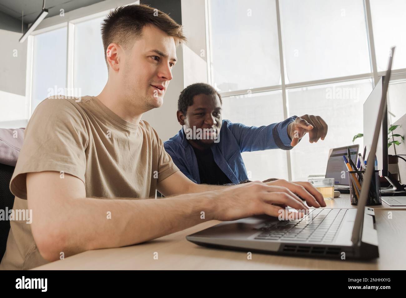Two programmers working in the office of a software development company. Coding technologies, site design. Successful diverse Teamwork. Cyberspace Stock Photo