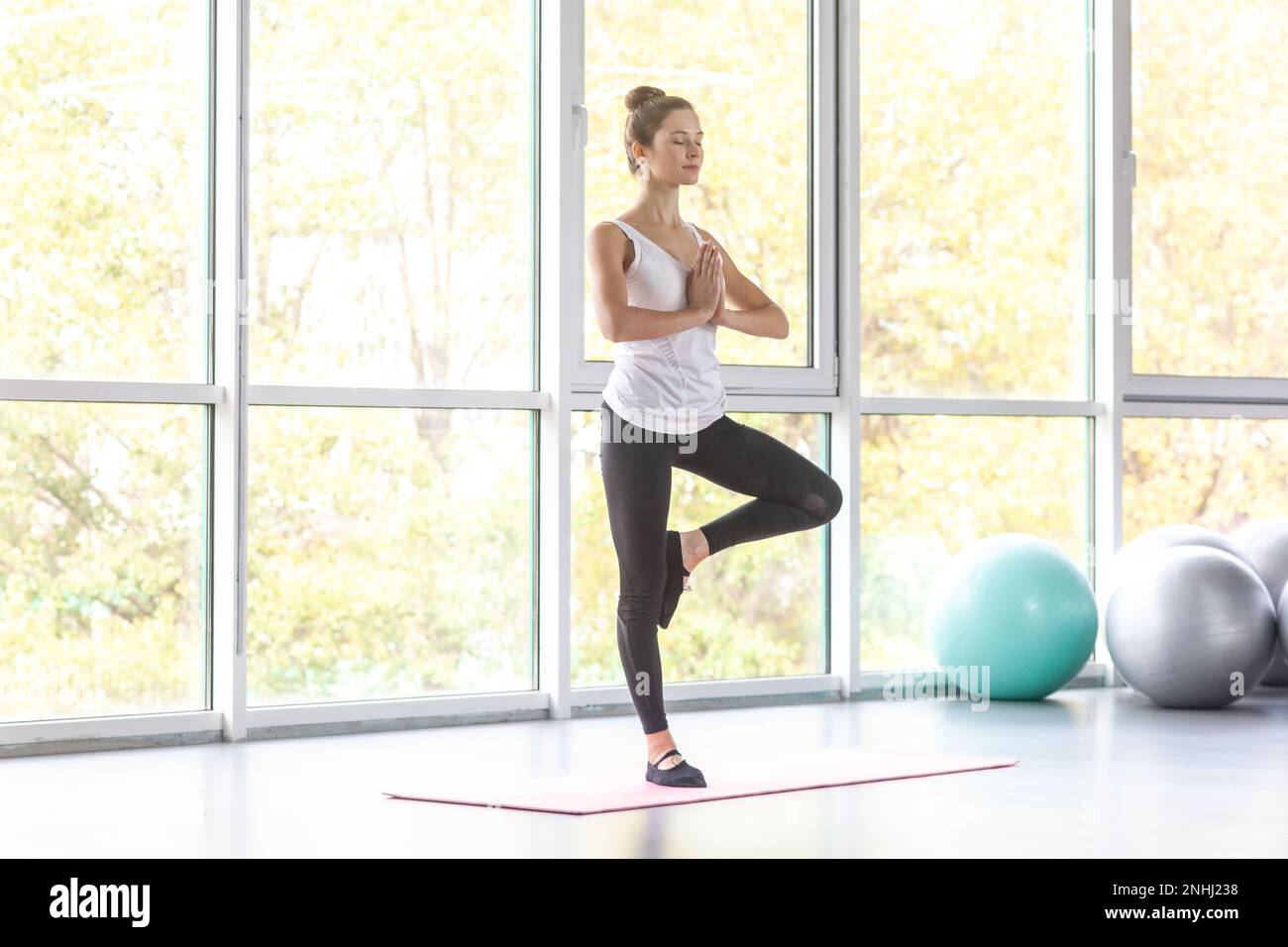 Tree pose. Portrait of sporty woman practicing yoga, doing Vrksasana ...