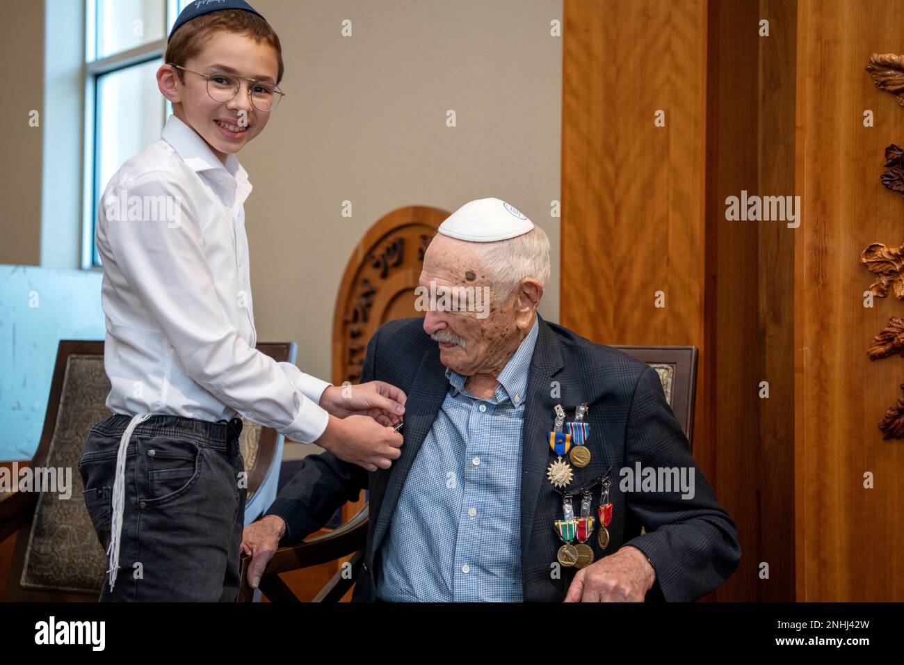 U.S. Army Air Corps 1st Lt. Gerald Teldon (right), retired, receives his Distinguished Unit Citation from his great grandson, Menachem Mendel Teldon, for his honorable service as a pilot on July 29, 2022, at the Chabad Center for Jewish Life and Learning, San Antonio, Texas. Teldon, born in the Bronx, N.Y., in 1924, joined the military in 1944. He completed 62 missions during WWII and the Korean War. Lt. Col. Andrew Stein, 502nd Operations Support Squadron commander, was the presiding officer. The awards presented to Teldon are as follows: the Air Medal; American Campaign Medal; European – Afr Stock Photo