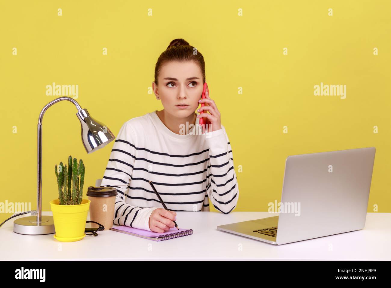 Concentrated secretary in striped shirt receiving calls on phone and ...