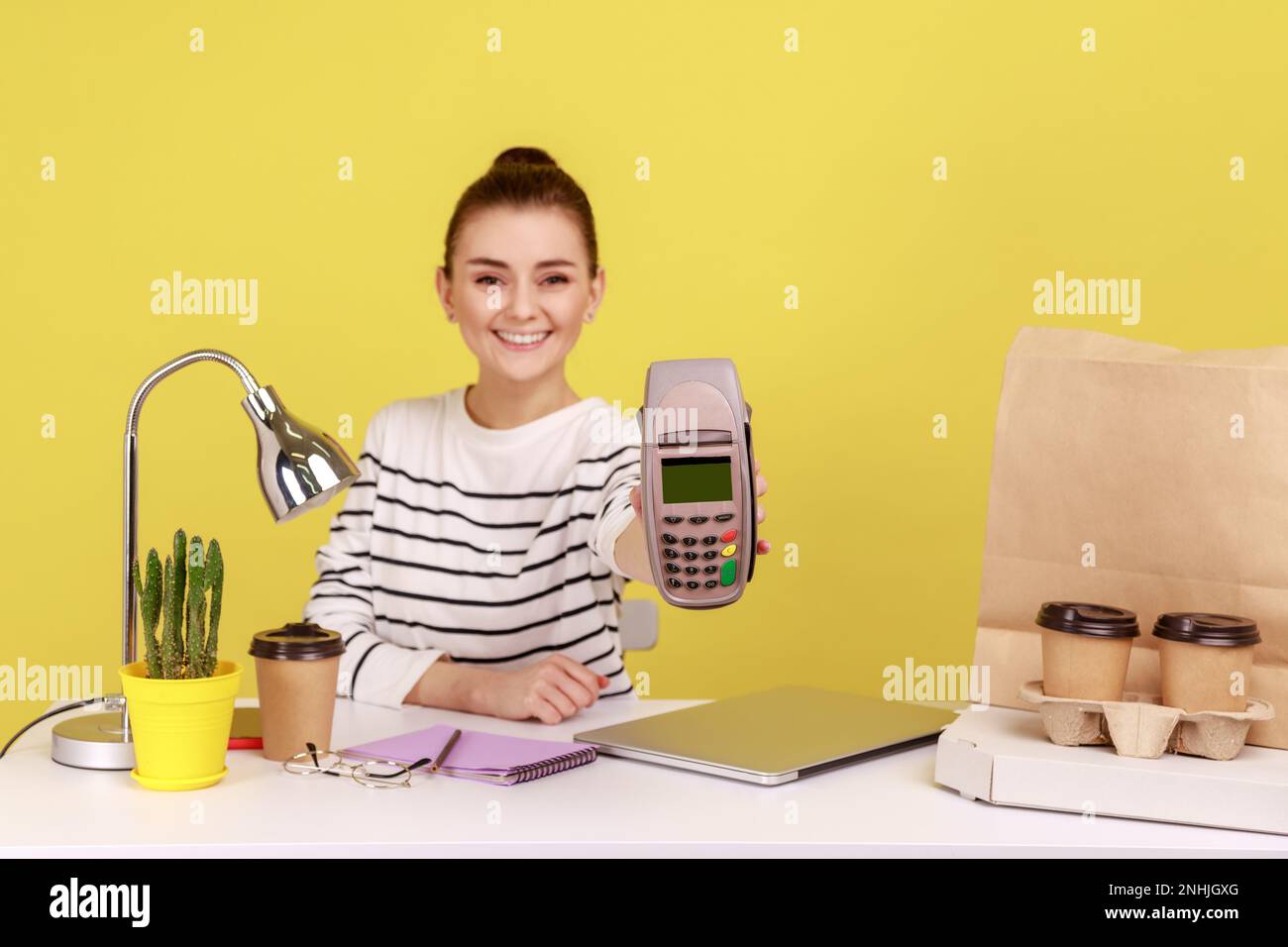Smiling positive woman holding in hand pos contactless payment terminal ...