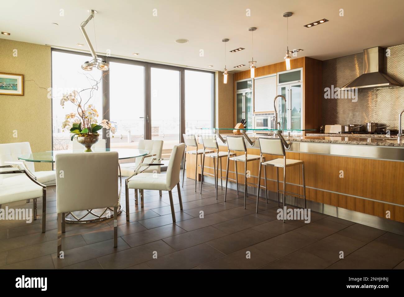 Round glass dining table with white leather chairs, wood and glass and island with grey
