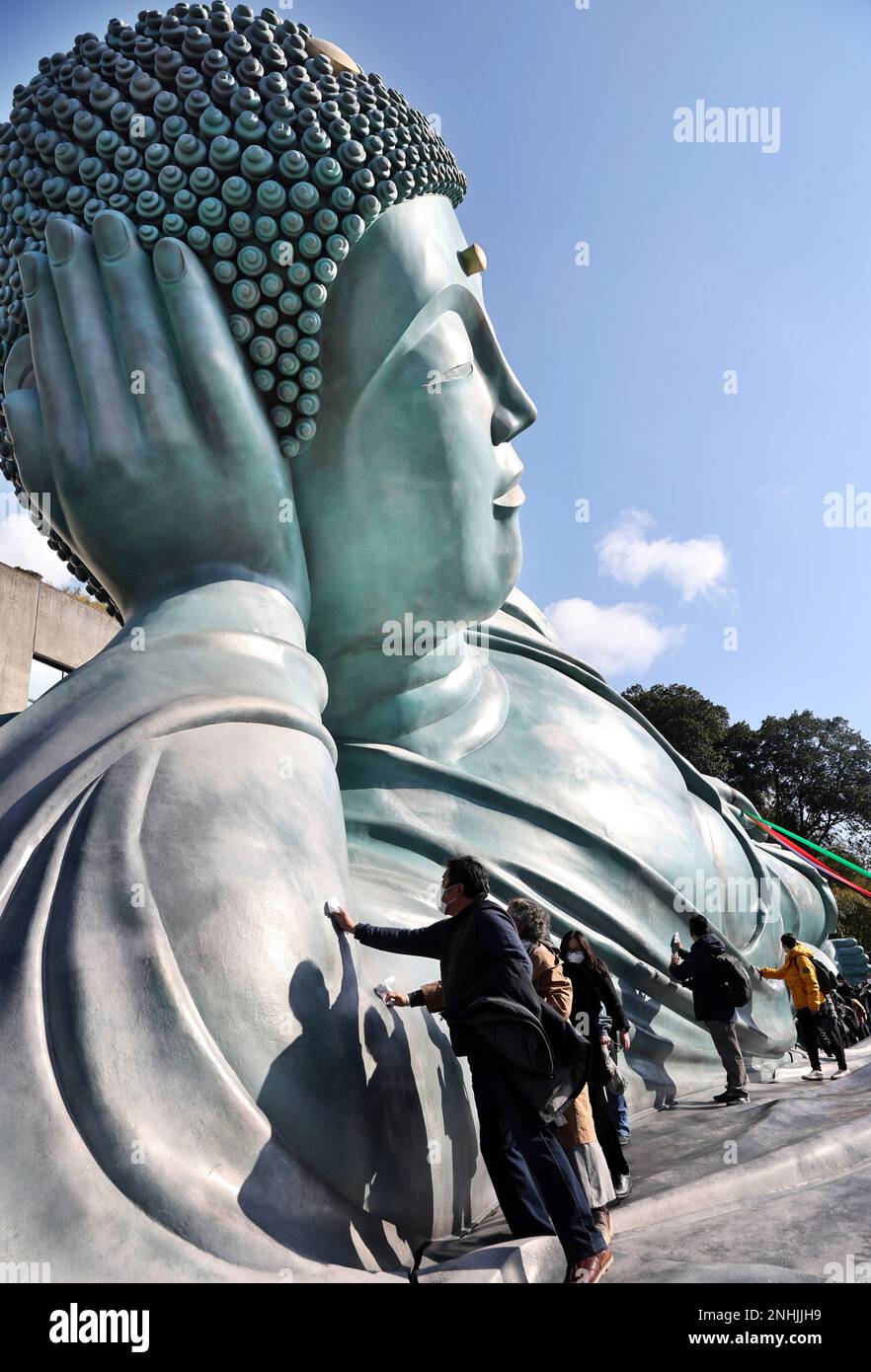 Approximately 200 Buddhist priests and believers clean a reclining