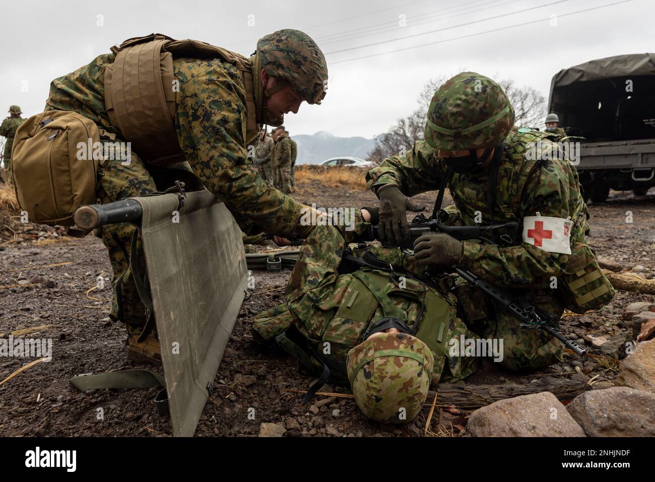 U.S. Navy corpsmen with the 31st Marine Expeditionary Unit, and a soldier with the 1st Amphibious Rapid Deployment Regiment, Japan Ground Self-Defense Force, prepare to lift a simulated casualty onto a stretcher during a mass casualty exercise at Hijudai, Japan on Feb. 19, 2023. The training simulated a mass casualty event granting the bi-lateral medical team an opportunity to actively practice medical care in the field with closely simulated pressure and conditions during Iron Fist 23. Iron Fist is an annual bilateral exercise designed to increase interoperability and strengthen the relations Stock Photo