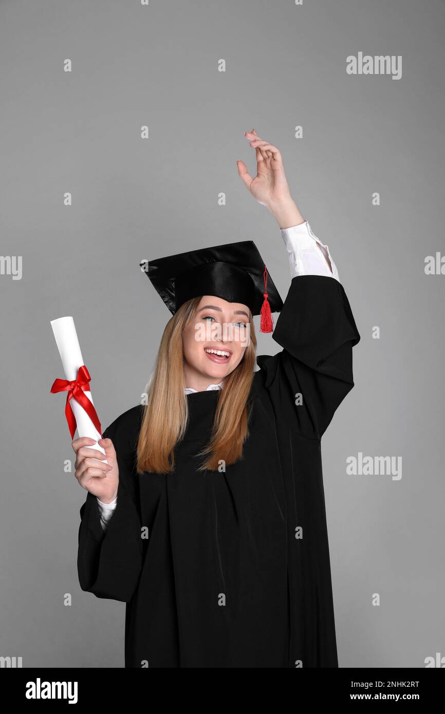 Happy student with diploma on grey background Stock Photo - Alamy