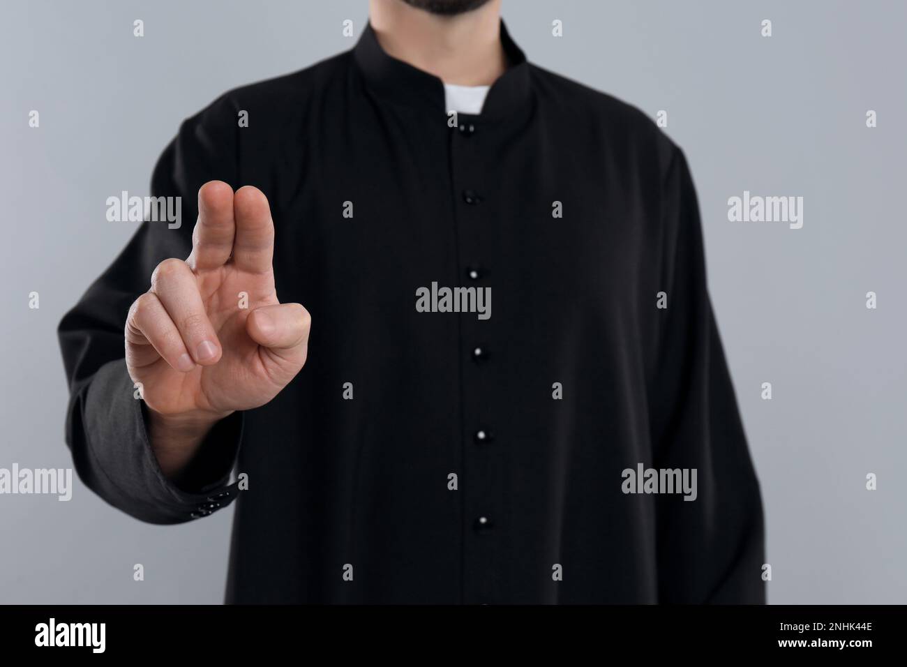 Priest making blessing gesture on grey background, closeup Stock Photo