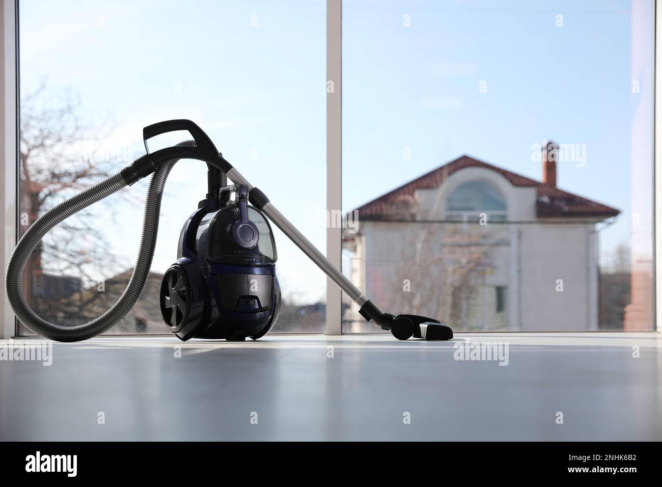 Modern vacuum cleaner near window indoors, space for text Stock Photo