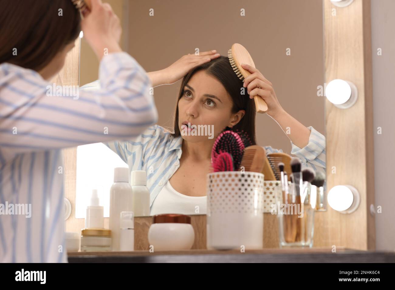 Young woman with hair loss problem near mirror indoors Stock Photo