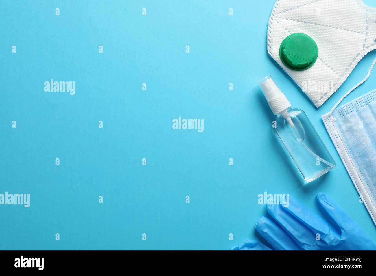 Medical gloves, masks and hand sanitizer on light blue background, flat