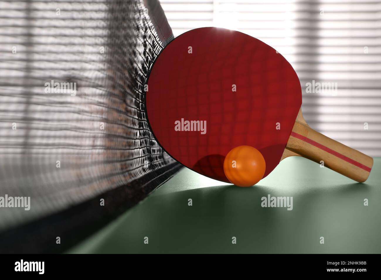 Racket and ball near net on ping pong table indoors Stock Photo