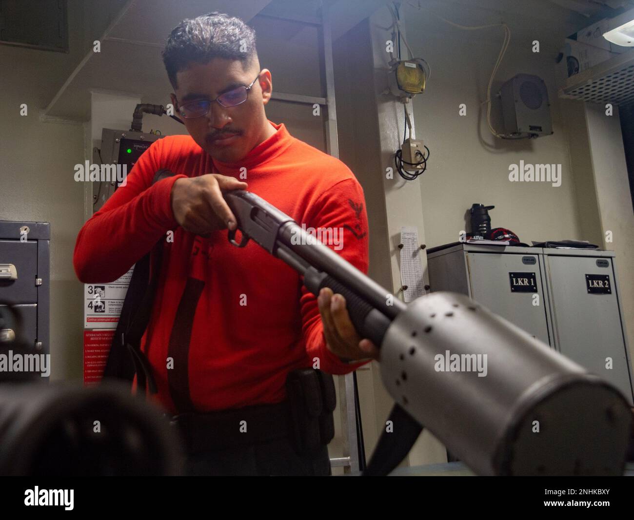 220730-N-YQ181-1032 SAN BERNARDINO STRAIT (July 30, 2022) Gunner’s Mate 3rd Class Alejandro Solano, from Chicago, performs a safety check on an M500 service shotgun in the armory aboard the U.S. Navy’s only forward-deployed aircraft carrier USS Ronald Reagan (CVN 76), in the San Bernardino Strait, July 30. Ronald Reagan, the flagship of Carrier Strike Group 5, provides a combat-ready force that protects and defends the United States, and supports alliances, partnerships and collective maritime interests in the Indo-Pacific region. Stock Photo