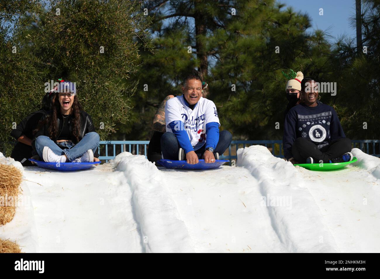 Emme Roberts (the daughter of Los Angeles Dodgers manager Dave Roberts),  left, Roberts and Dodgers Foundation chief executive officer Nichol Whitman  slide down a snow sledding hill during the Dodgers Foundation Holiday