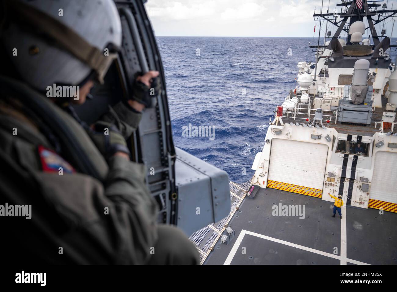 PACIFIC OCEAN (July 30, 2022) U.S. Navy Petty Officer 1st Class Humberto Alba, a naval aircrewman tactical-helicopter, attached to Helicopter Maritime Strike Squadron (HSM) 37, deployed on U.S. Coast Guard Legend-class cutter USCGC Midgett (WMSL 757), looks down at a USCGC crewmember after taking off during flight operations during Rim of the Pacific (RIMPAC) 2022. Twenty-six nations, 38 ships, three submarines, more than 170 aircraft and 25,000 personnel are participating in RIMPAC from June 29 to Aug. 4 in and around the Hawaiian Islands and Southern California. The world's largest internati Stock Photo