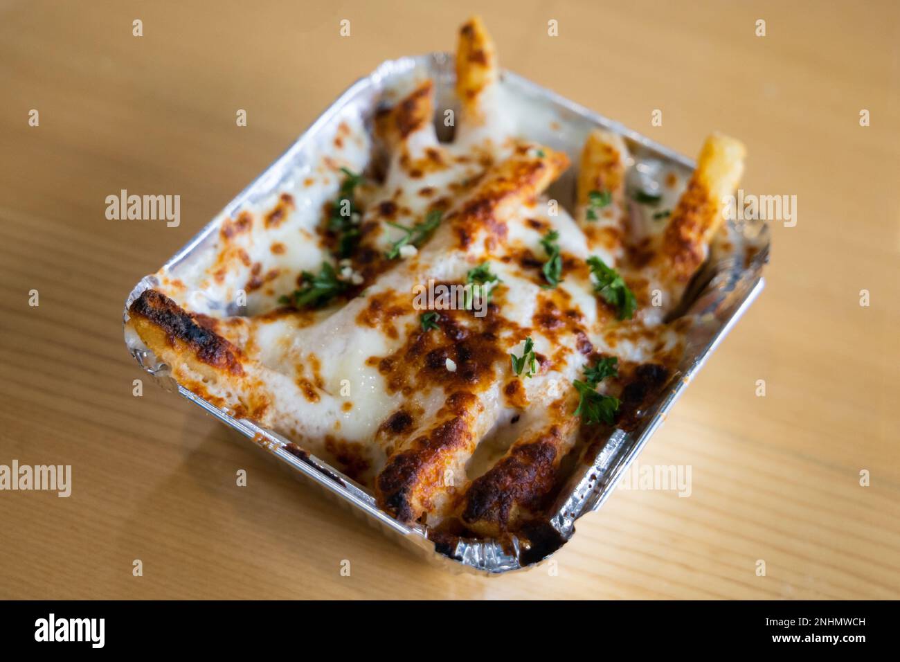 a metal take out container with baked Greek french fries loaded with
