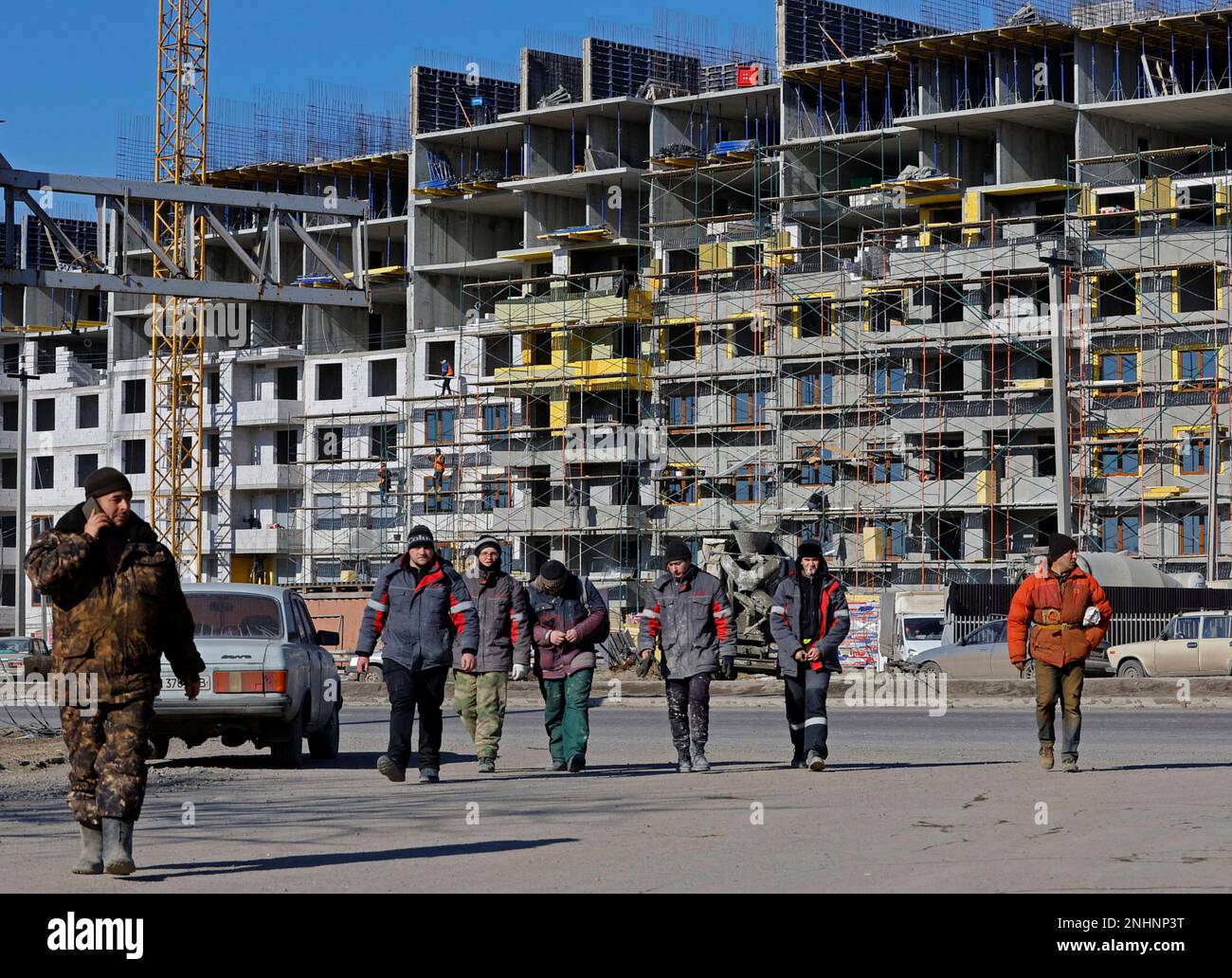 Workers walk in front of an apartment building under construction, in the course of Russia-Ukraine conflict in Mariupol, Russian-controlled Ukraine, February 10, 2023. REUTERS/Alexander Ermochenko Stock Photo