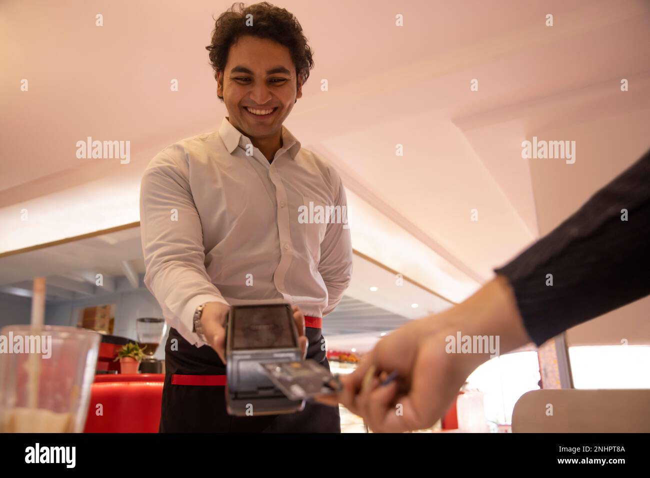 Waiter holding card reader while customer making payment through credit