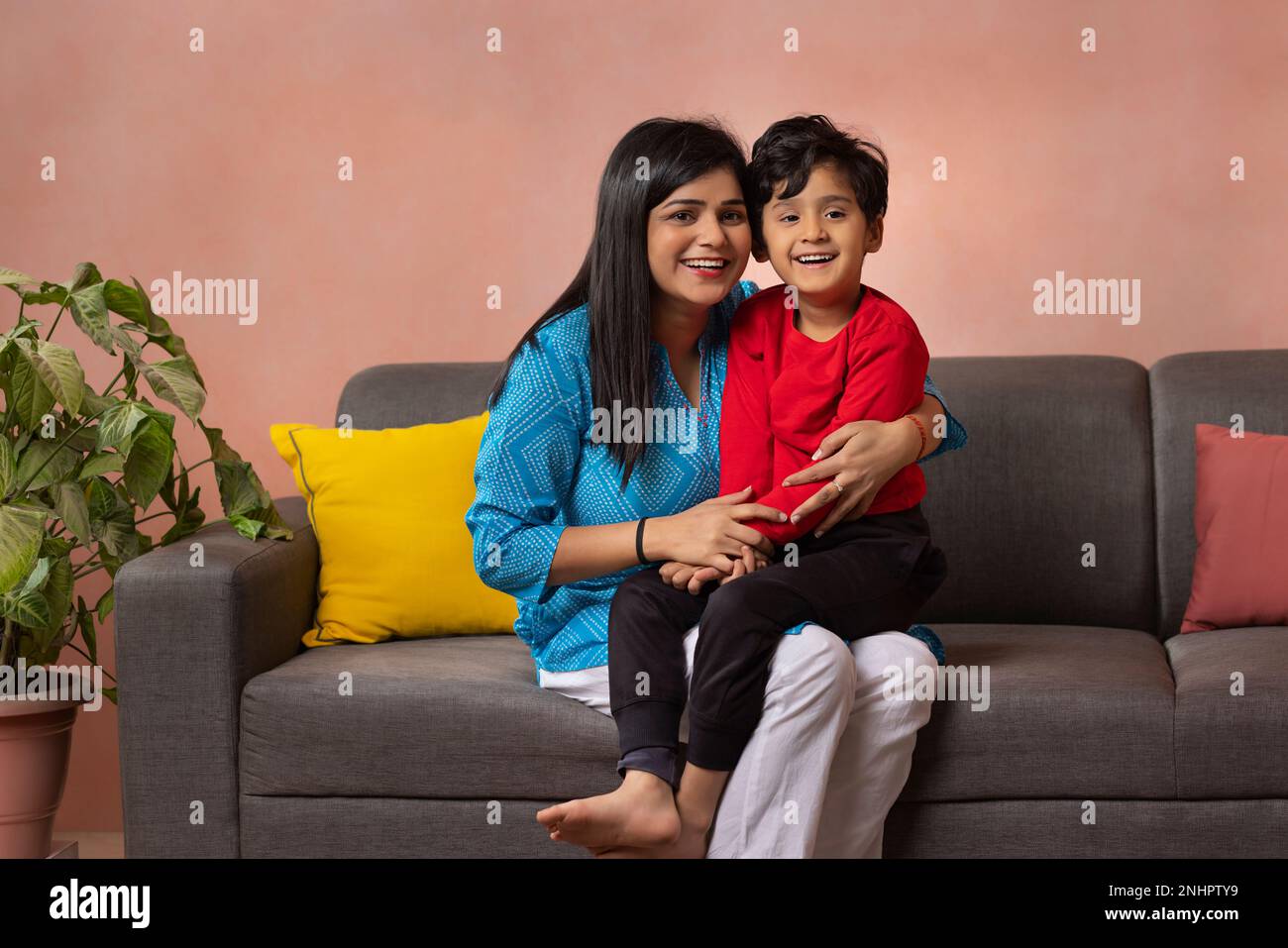 Portrait of happy mother and son sitting on sofa in living room Stock Photo