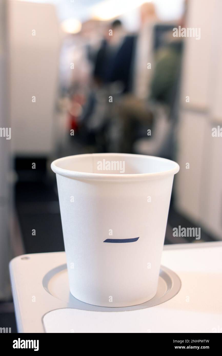 A drink in a paper cup on a passenger's table in a flying airplane ...