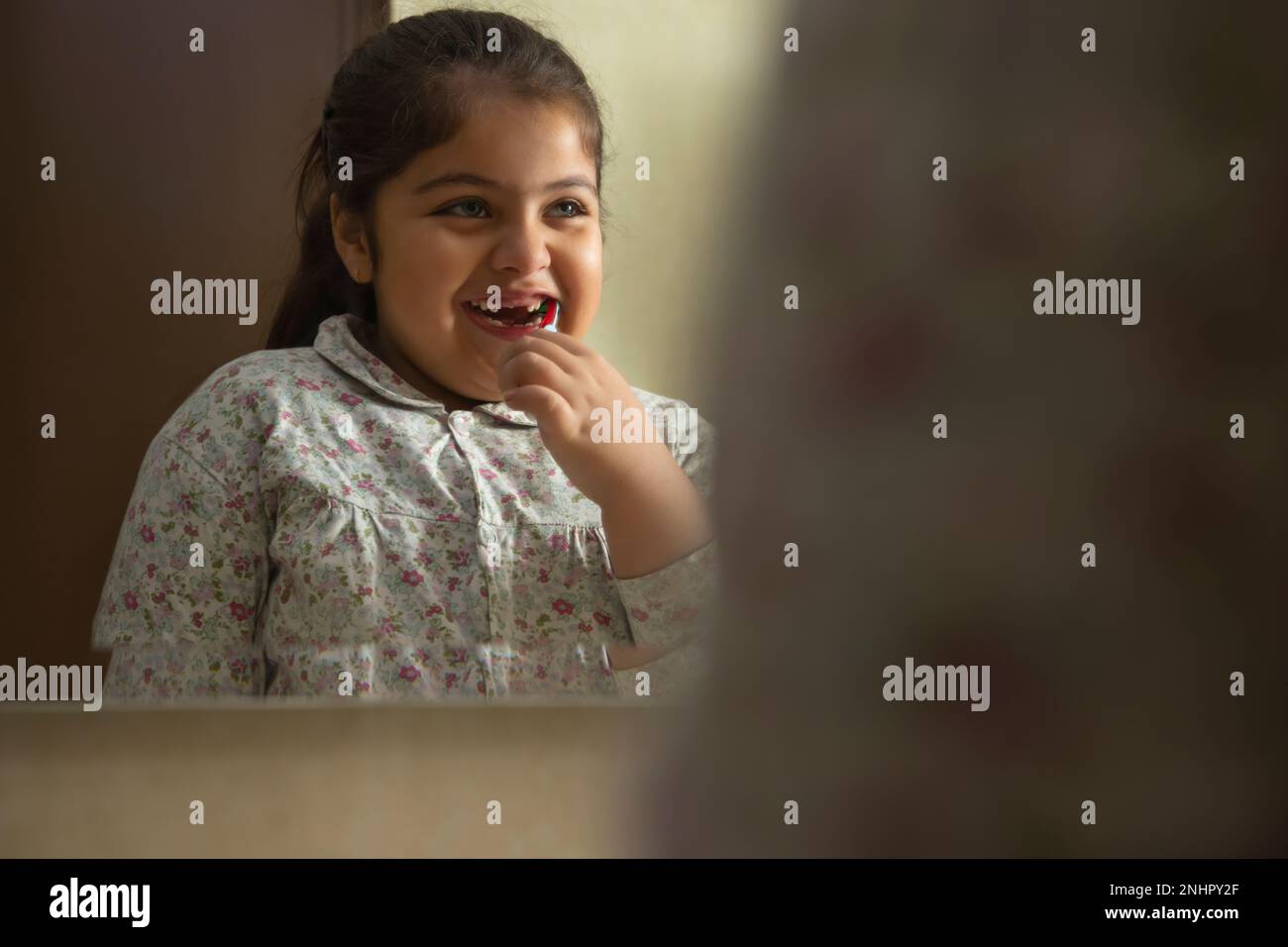 Portrait of little girl brushing teeth in front of mirror Stock Photo